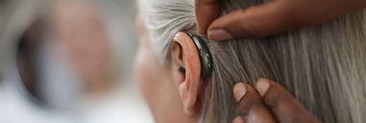 Closeup image of a new hearing aid on a woman's ear